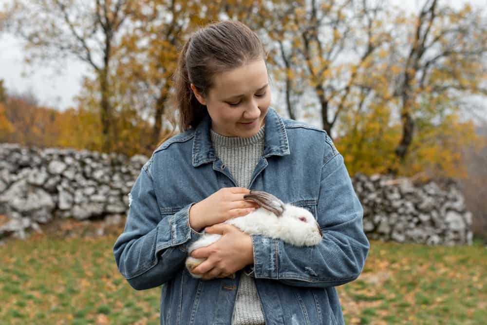 A lady carrying a small rabbit. Rabbits can be emotional support animals too.